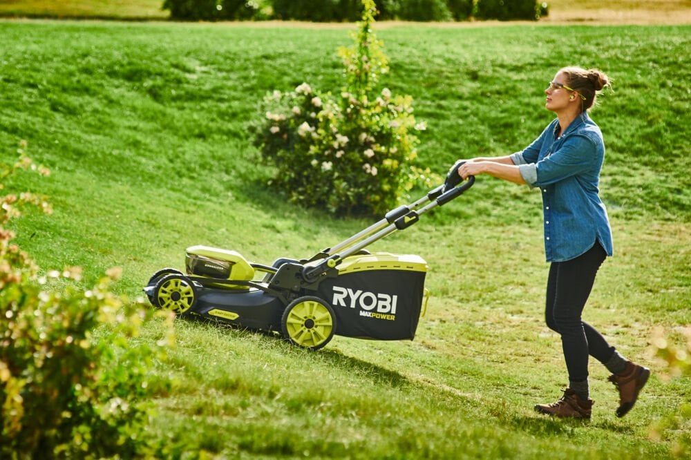 Kobieta używa kosiarki akumulatorowej na trudnym terenie o mocnym nachyleniu