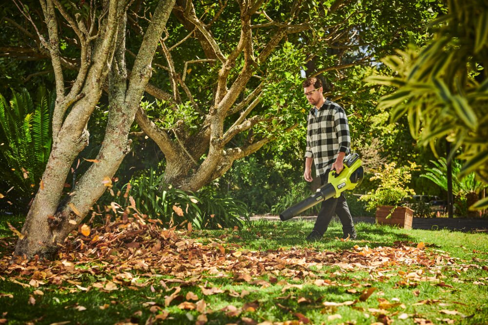 Bezszczotkowa dmuchawa WHISPER™ 36V MAX POWER w użyciu do sprzątania liści w ogrodzie