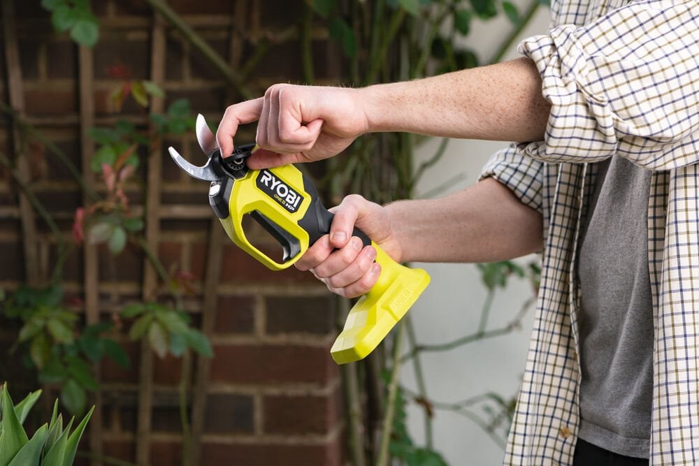 Mężczyzna trzyma w rękach bezszczotkowy sekator akumulatorowy ONE+™ HP 18V