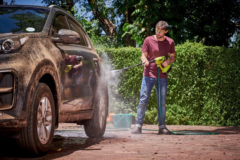 Mężczyzna myje auto z pomocą akumulatorowej myjki ciśnieniowej