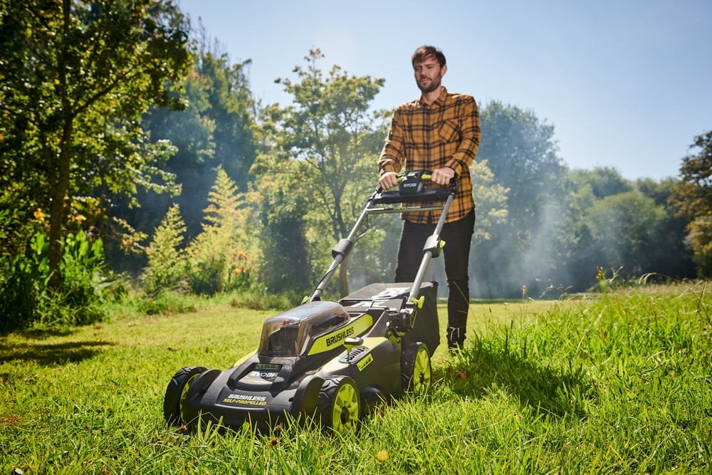 Mężczyzna kosi wysoką trawę na zaniedbanym trawniku