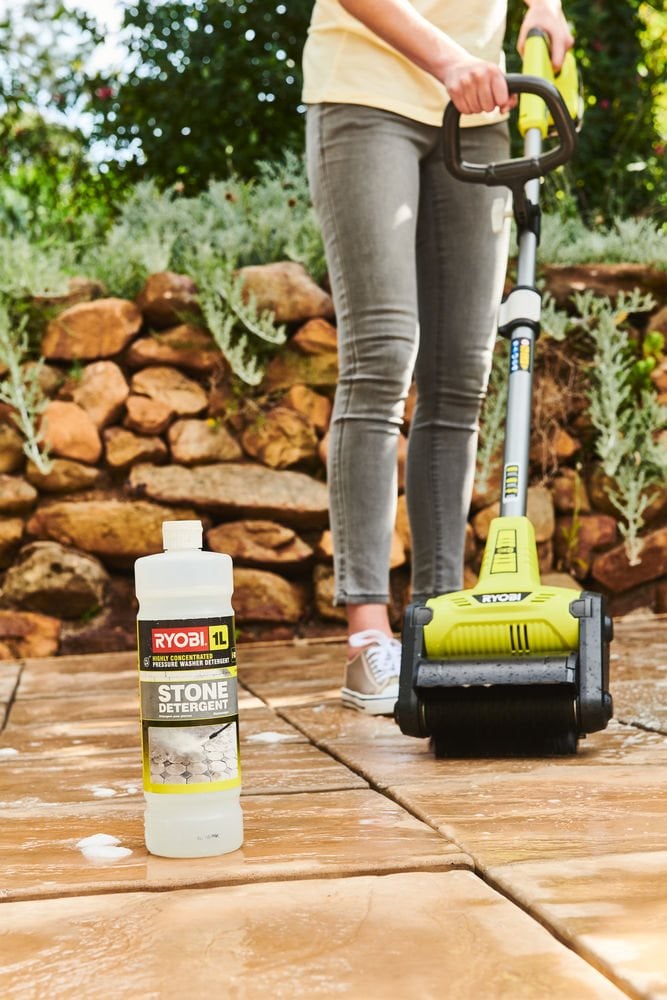 Kobieta usuwa mech z patio za pomocą specjalnej szczotki