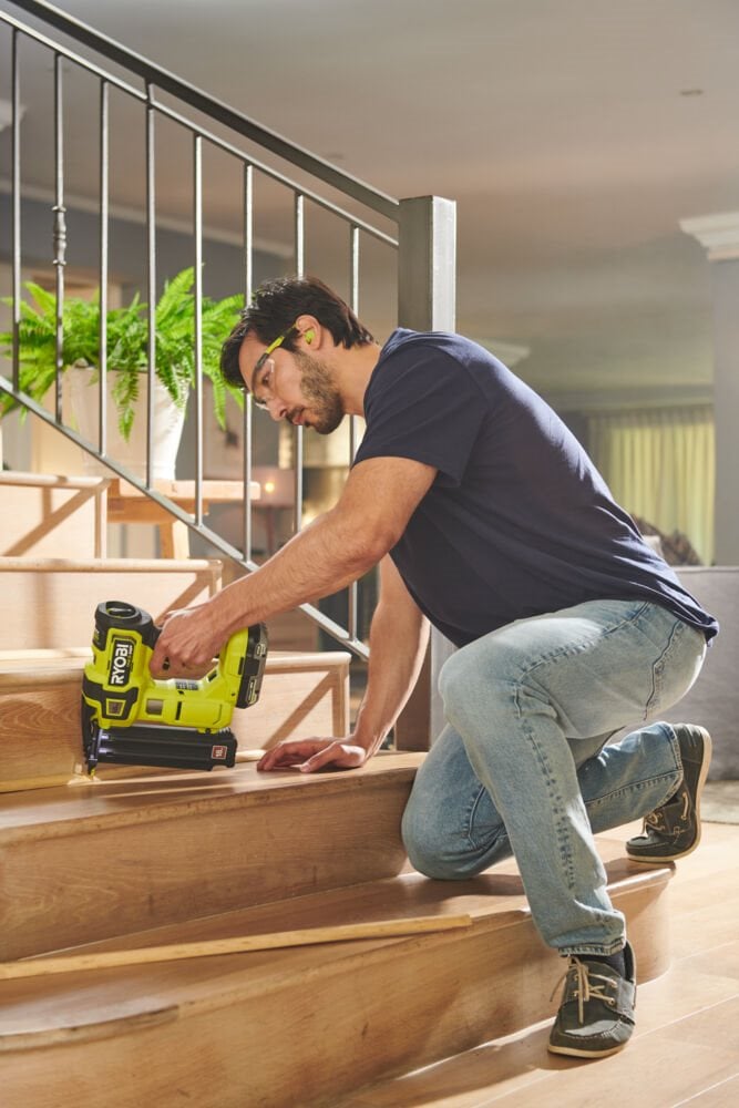 Mężczyzna używa bezszczotkowej sztyfciarki do montażu schodów