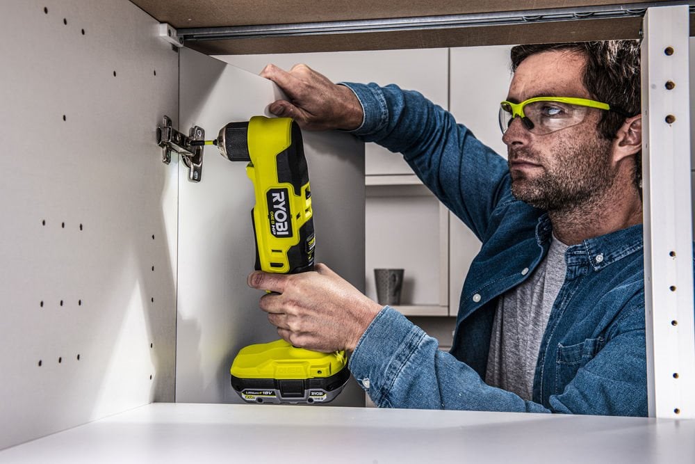 Mężczyzna używa bezszczotkowej wiertarki kątowej do mocowania zawiasów