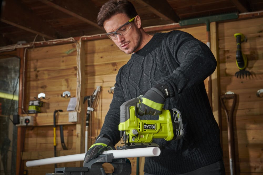 Mężczyzna używa wyrzynarki RYOBI 18V w warsztacie stolarskim